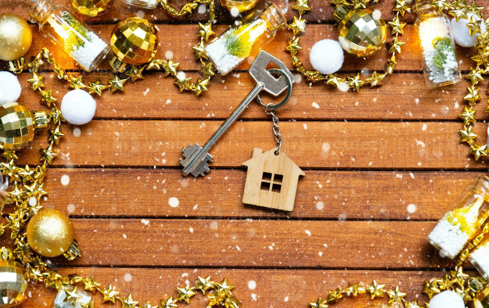 Key to house with a keychain tiny home on wooden background with Christmas decor layout. Gift for New Year, Christmas. Building, project, moving to new house, mortgage, rent and purchase real estate photo