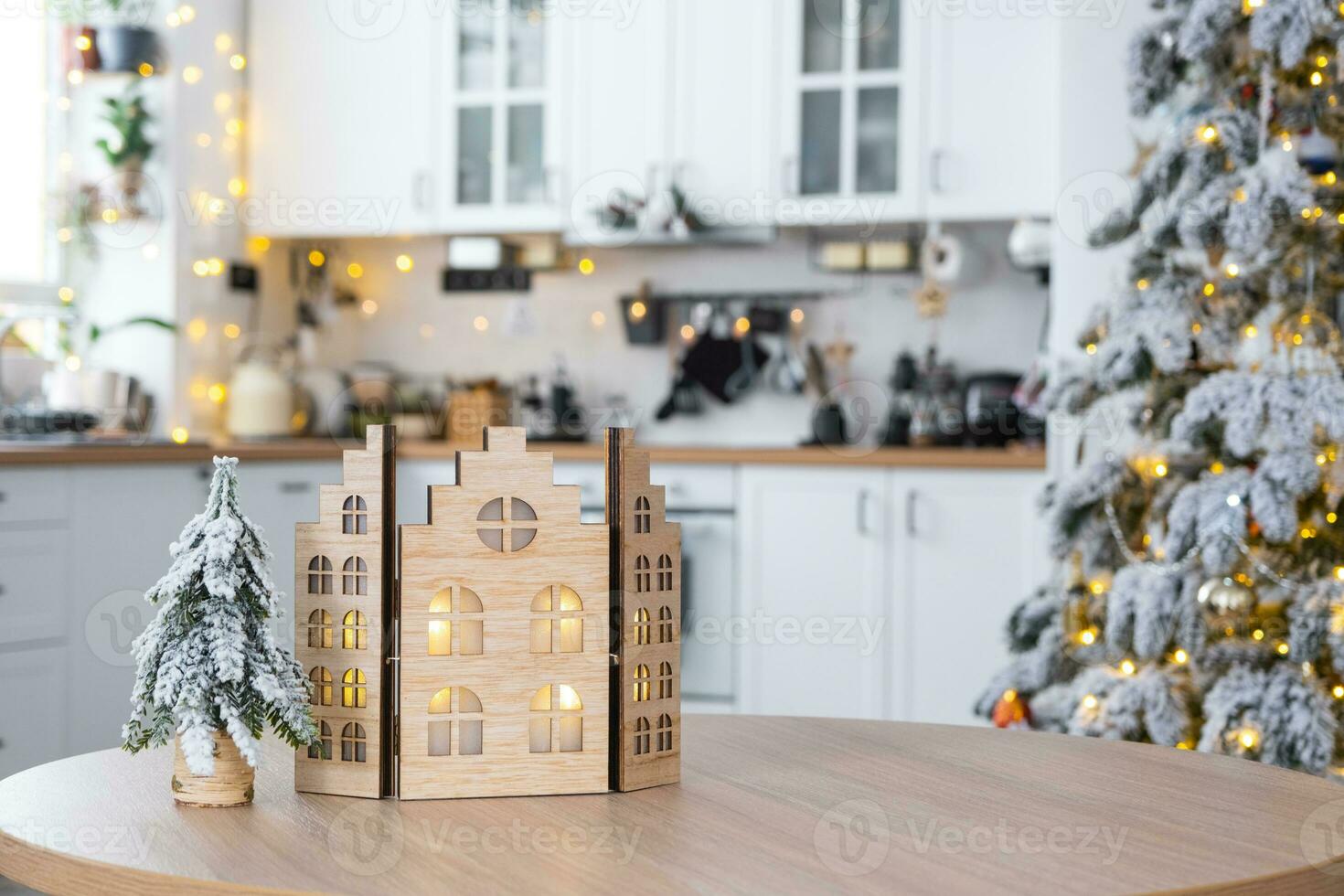 Cozy Christmas decor tiny house of small size on table of festive white modern kitchen. Gift for New Year. Insurance, moving to new house, mortgage, rent and purchase real estate photo