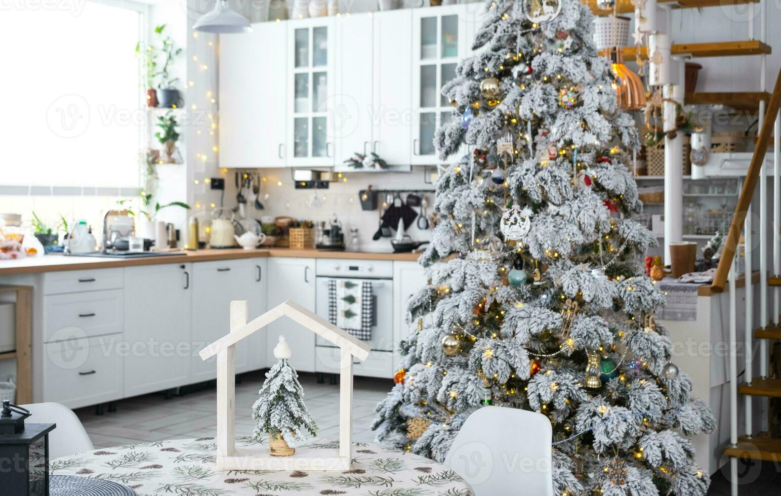 festivo Navidad decoración en blanco cocina, moderno pueblo interior con un Nevado Navidad árbol y hada luces. nuevo año, Navidad ánimo, acogedor hogar, metal modular escalera. el general plan foto