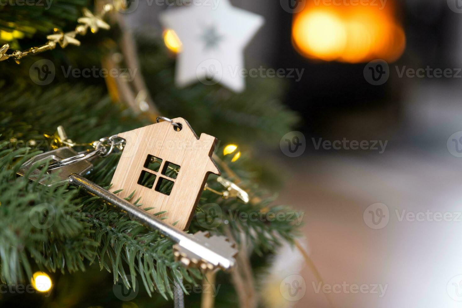 Key to the house with a keychain is hanging on the Christmas tree. A gift for New Year, Christmas. Building, design, project, moving to new house, mortgage, rent and purchase real estate. Copy space photo