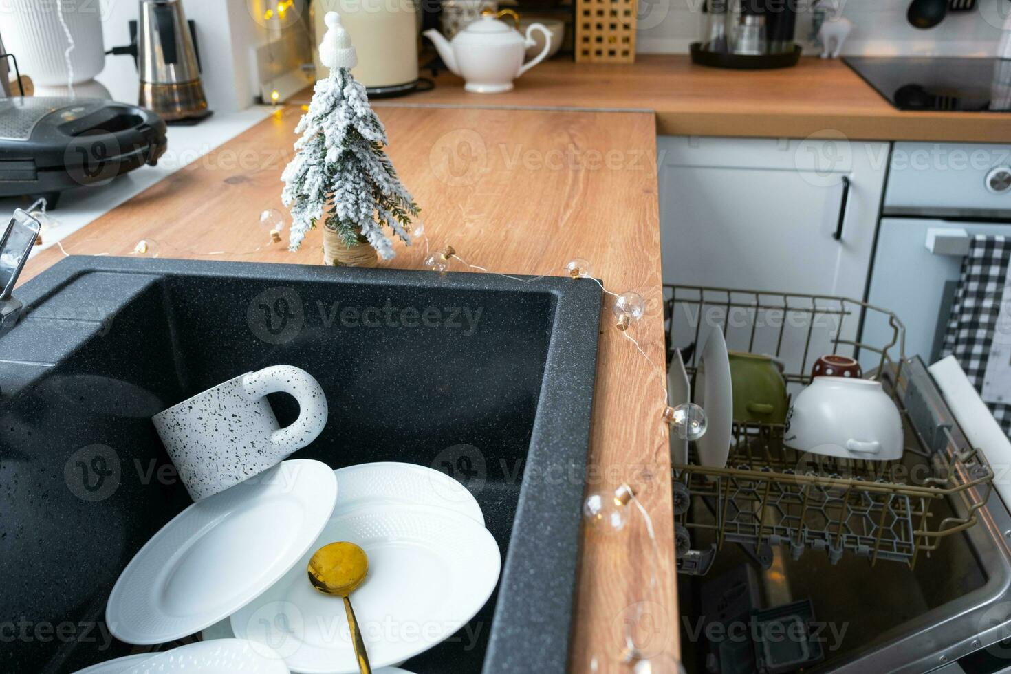 Dirty dishes in the sink in the garlanded kitchen, a holiday after a feast at Christmas. Mess after the guests for the New Year, kitchen cleaning, detergent, cleaning services photo