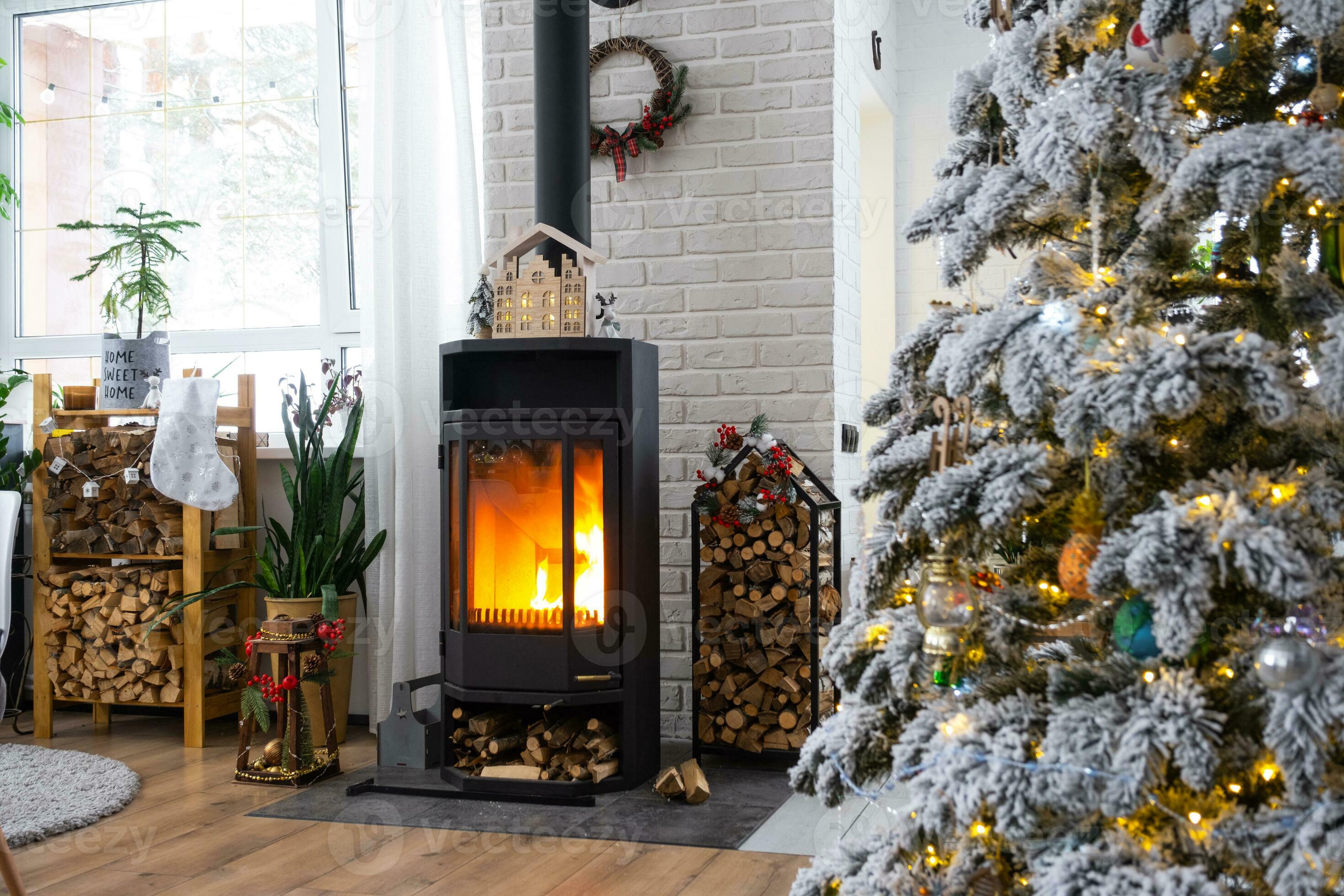 Metall black stove, burning hearth fireplace in white Festive interior of house is decorated for 