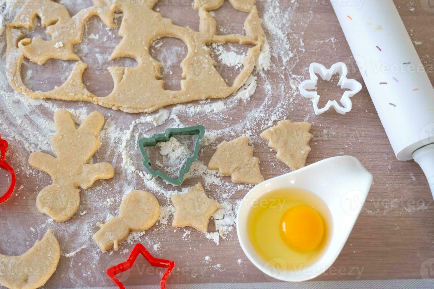 diseño de Galleta cortadores de cerca cortar fuera galletas desde el masa con moldes en un Navidad tema en el formar de un muñeco de nieve, un Navidad árbol, estrellas en el cocina foto