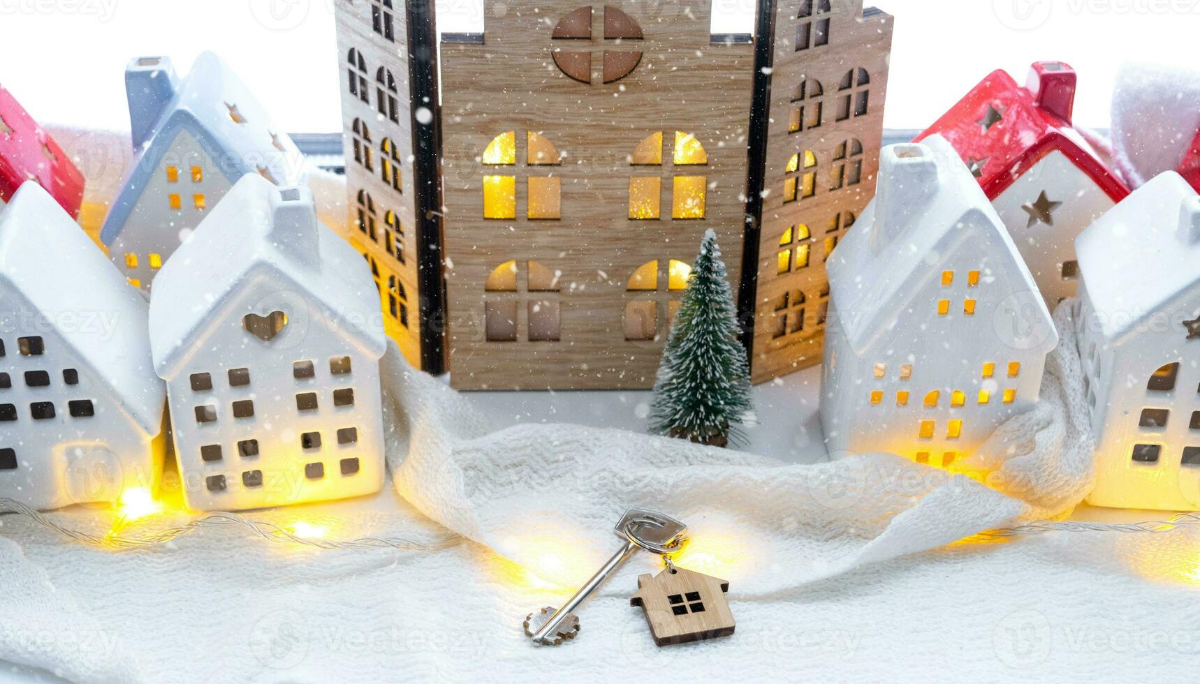 Key and tiny house of a small size on cozy home with Christmas decor on window sill. Gift for New Year. Insurance, moving to new house, mortgage, rent and purchase real estate photo