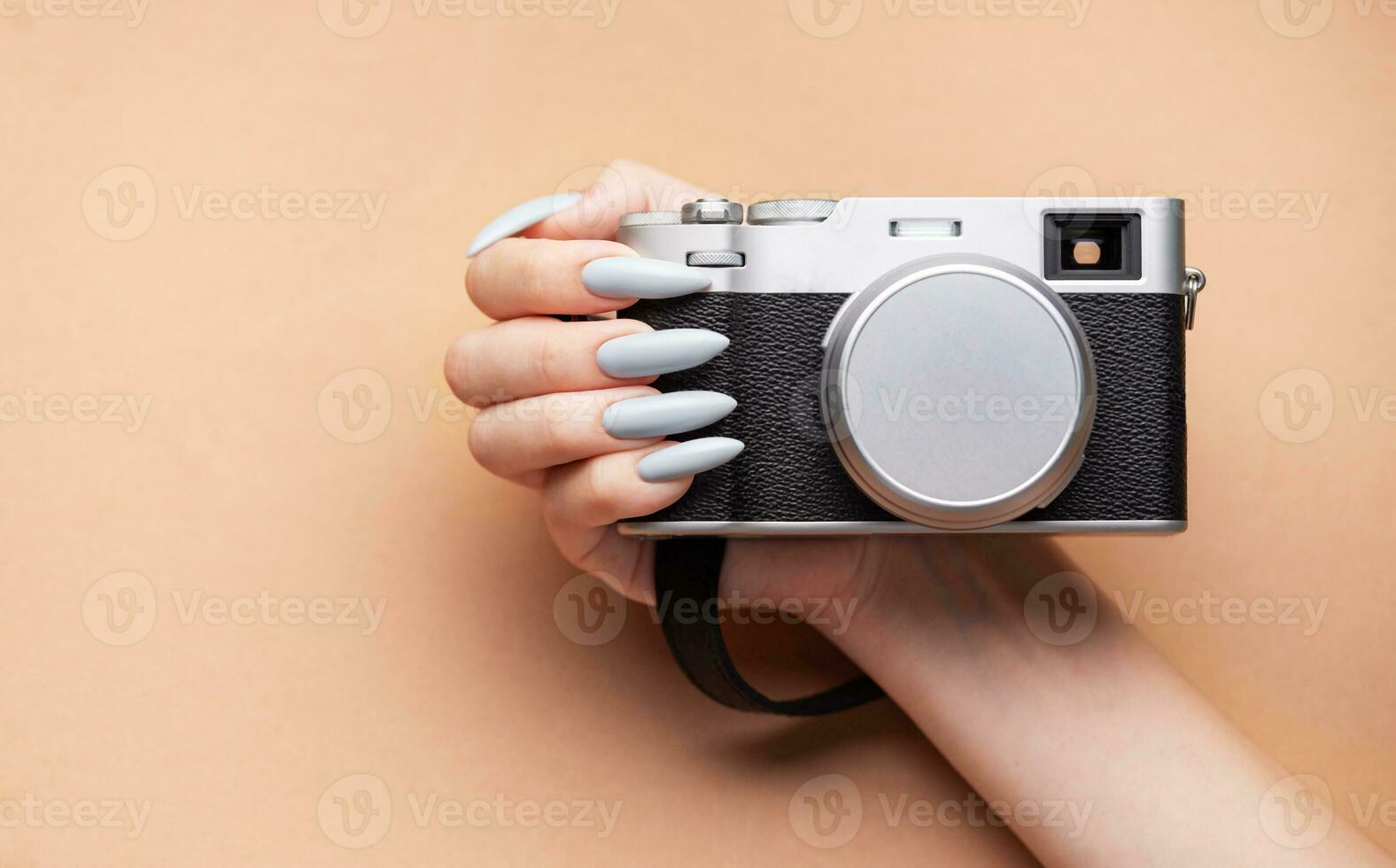 Woman's hand with grey nail polish holding camera photo