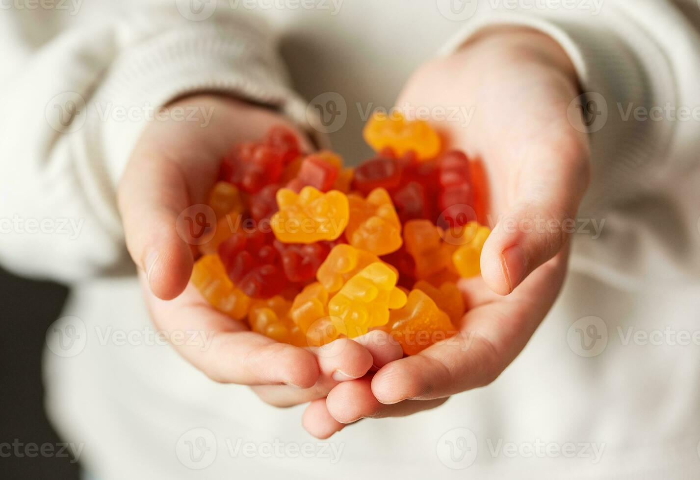 A girl holds a gummy bear vitamines in her hands photo