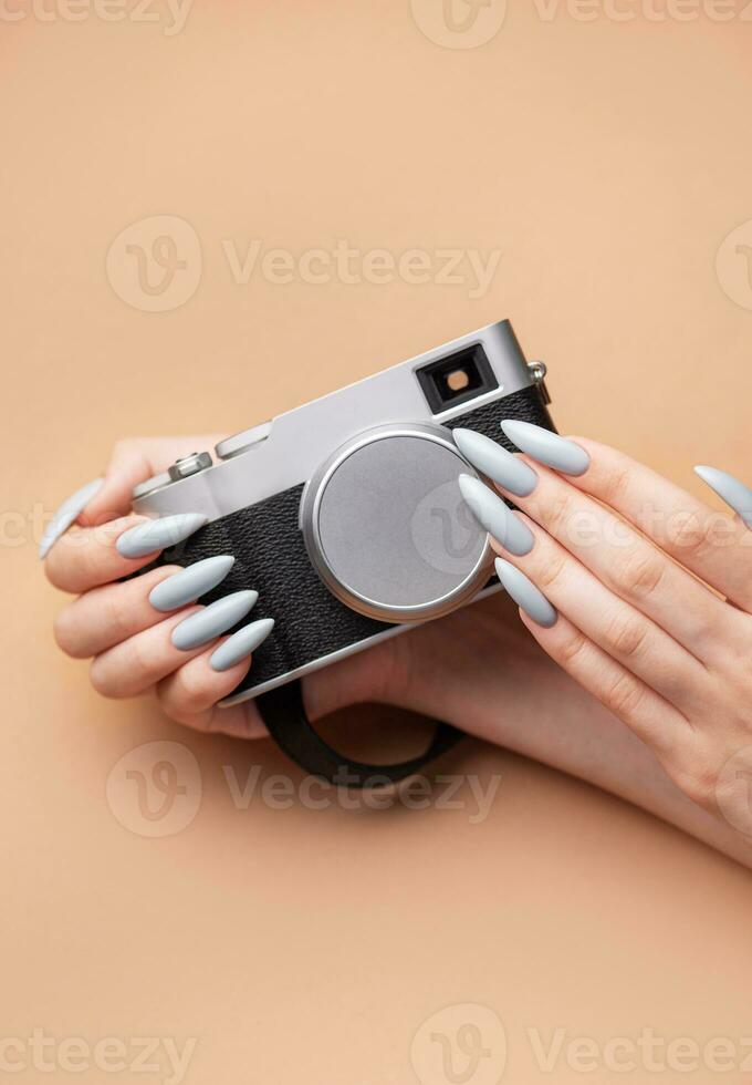 Woman's hand with grey nail polish holding camera photo