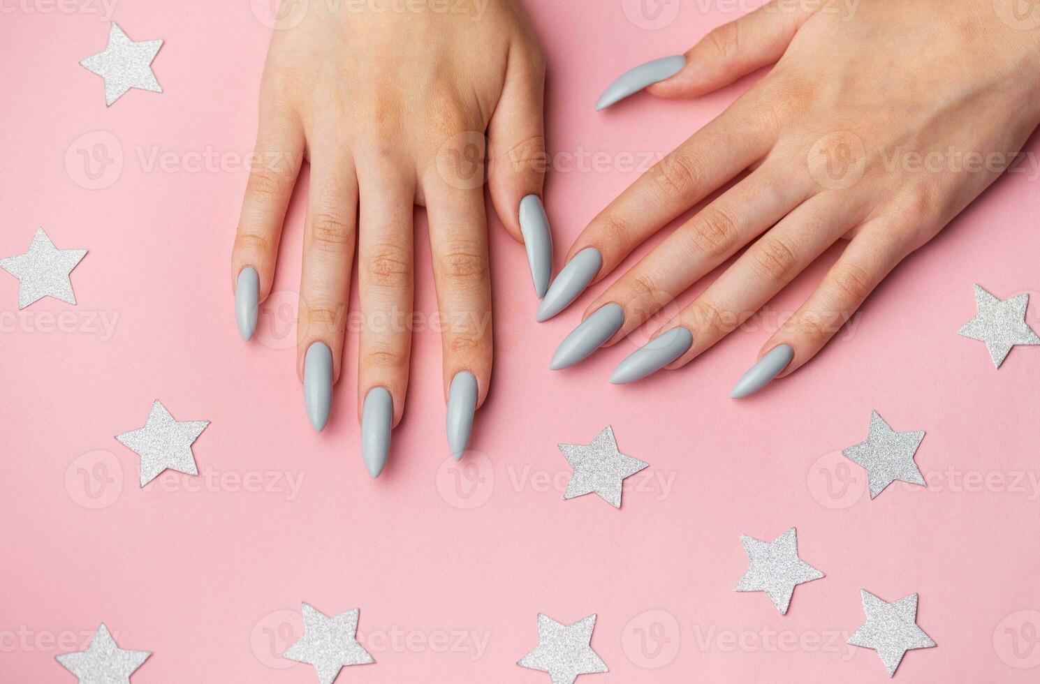 Hands with grey manicure on a pink background photo