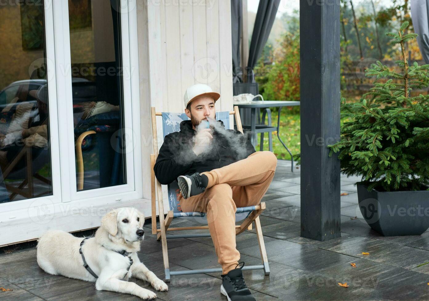 Young man sitting with dog on terrace photo