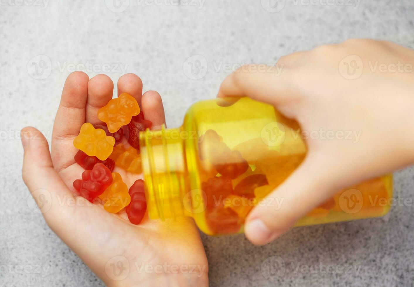 A girl holds a gummy bear vitamines in her hands photo