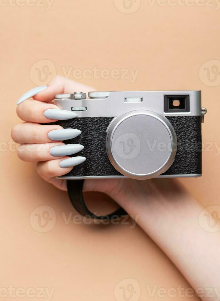 Woman's hand with grey nail polish holding camera photo
