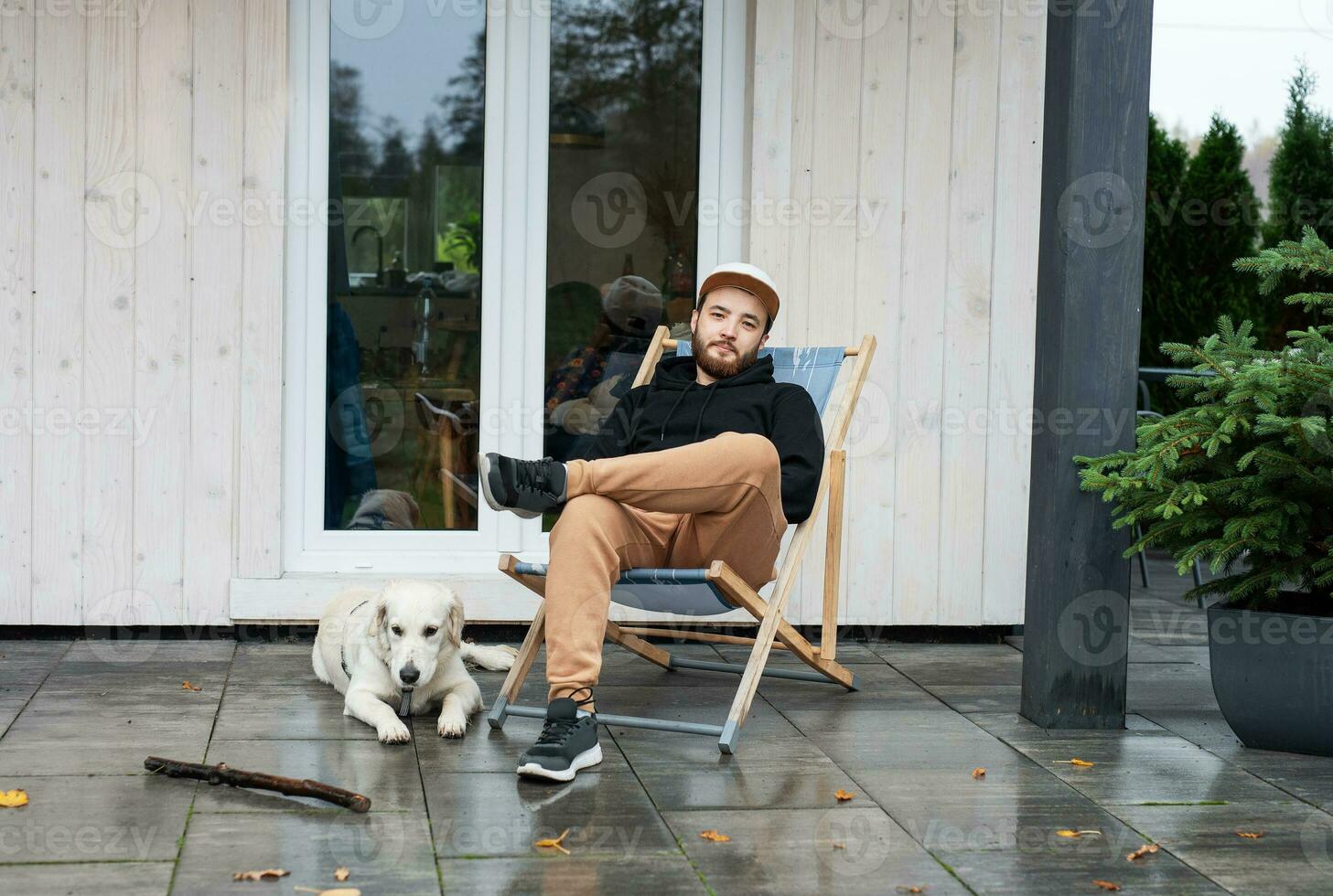 Young man sitting with dog on terrace photo