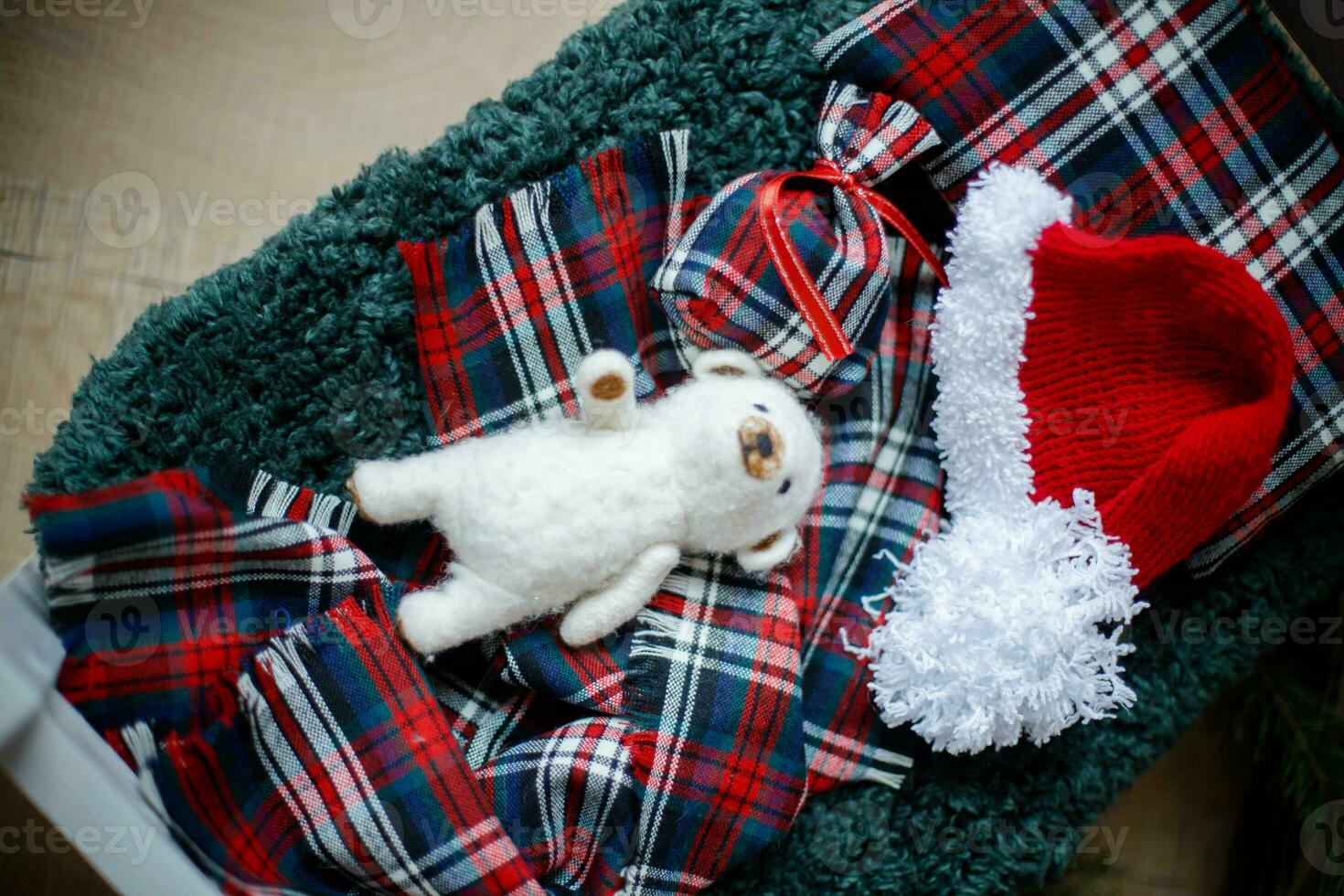 Santa Claus hat and teddy bear on a plaid fabric. photo