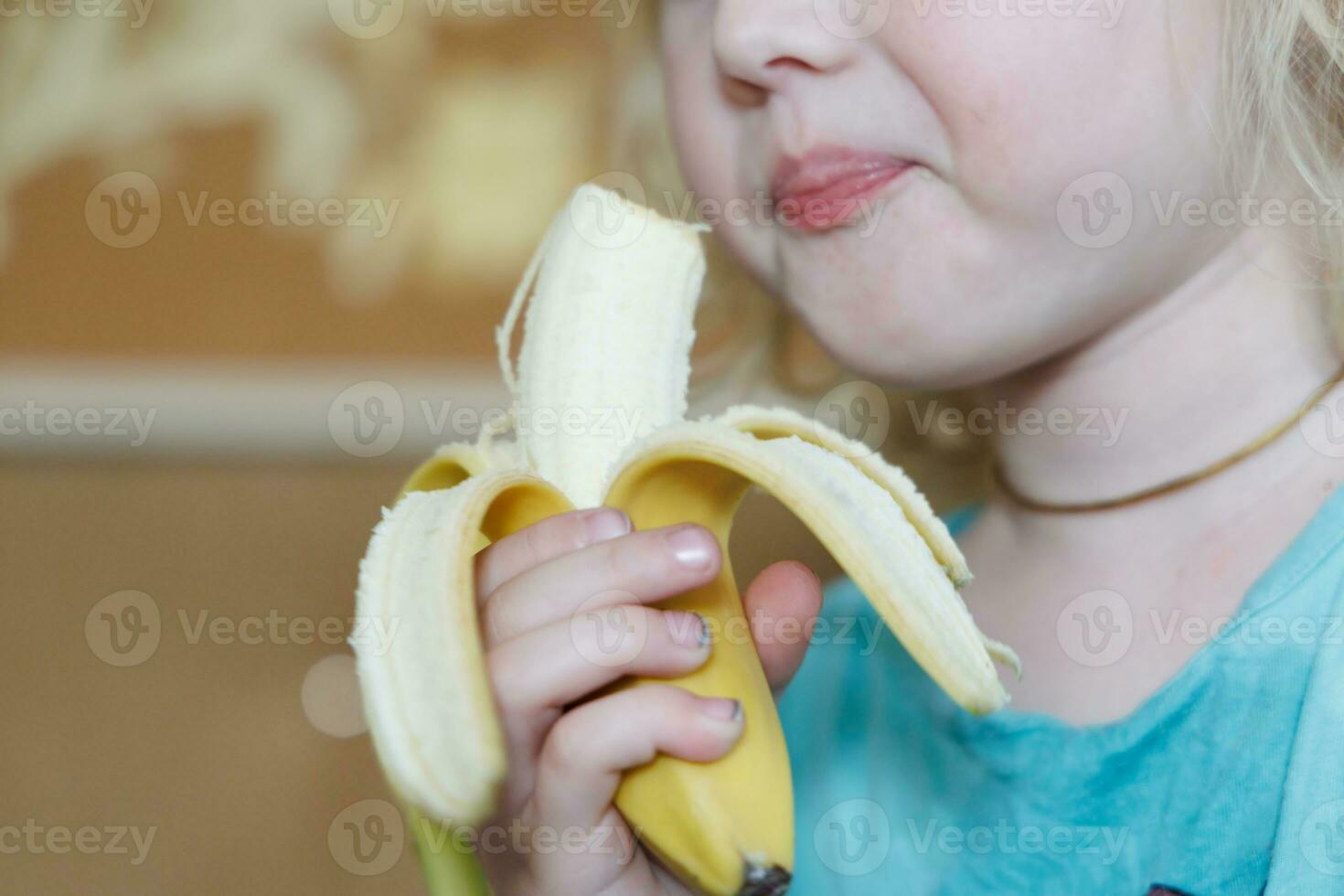 Portrait of a little girl eating a banana. The concept of healthy food. A fresh quick snack photo