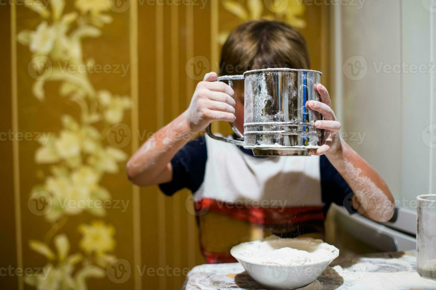 A little boy is playing with flour and milk in the kitchen. photo