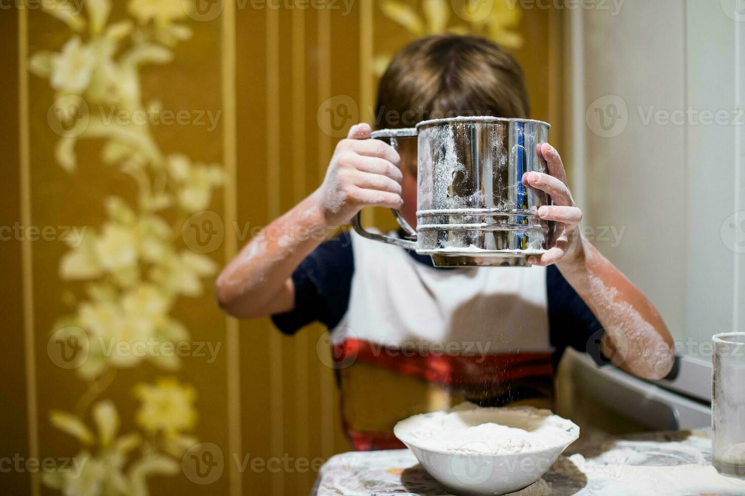 un pequeño chico es jugando con harina y Leche en el cocina. foto