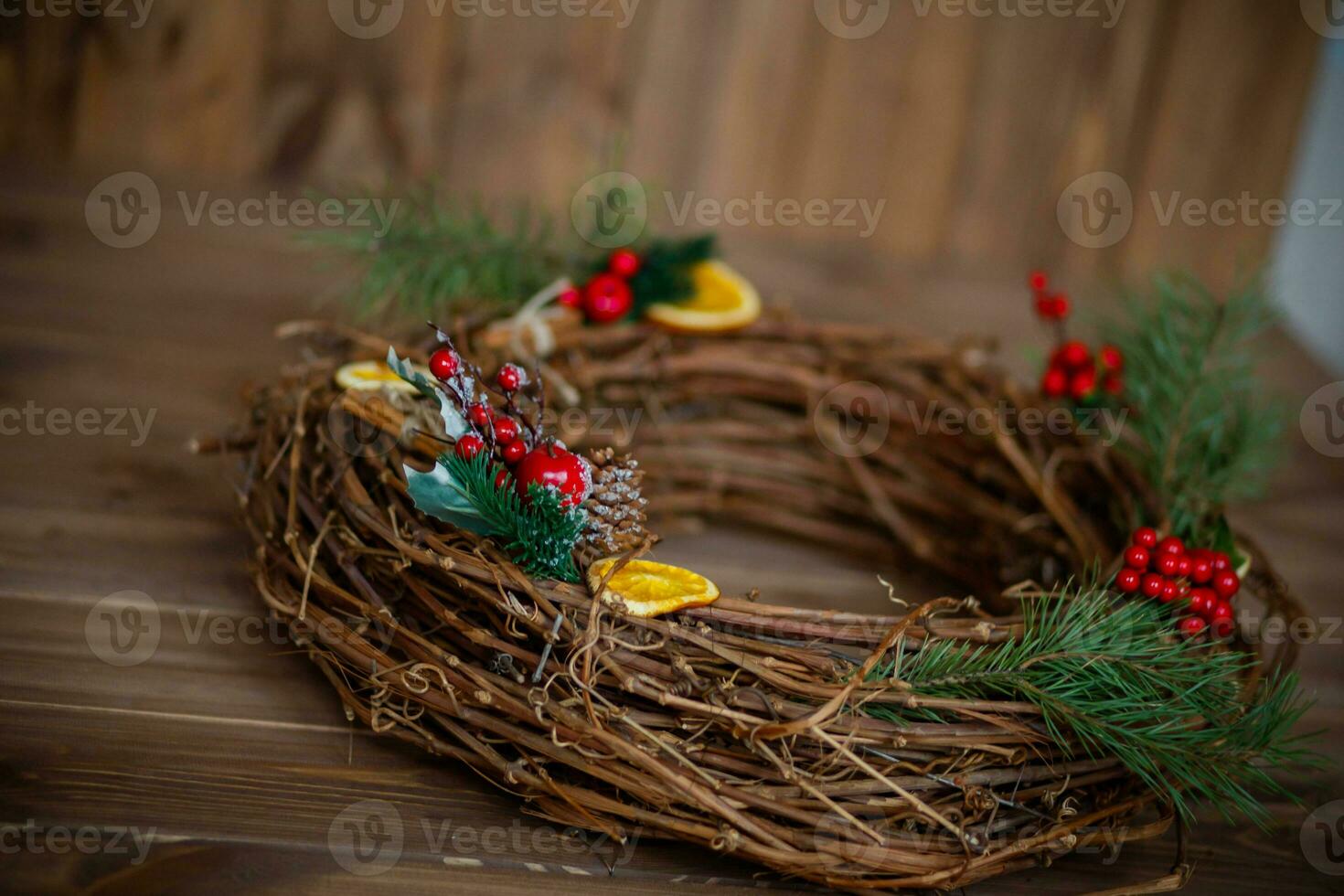 Christmas wreath on a wooden background. Christmas wreath made of twigs, berries and oranges. photo