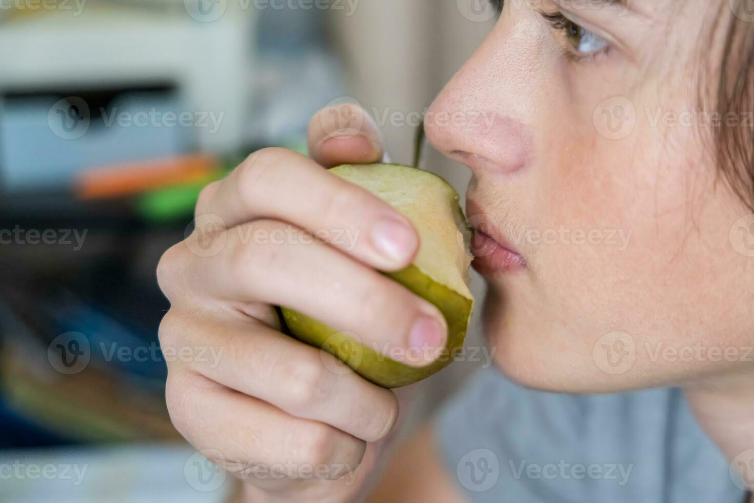 portrait of a teenage boy eating a pear. Close-up photo