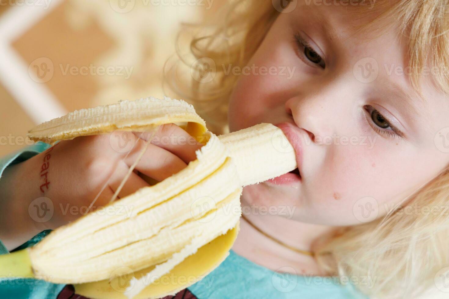 Portrait of a little girl eating a banana. The concept of healthy food. A fresh quick snack photo