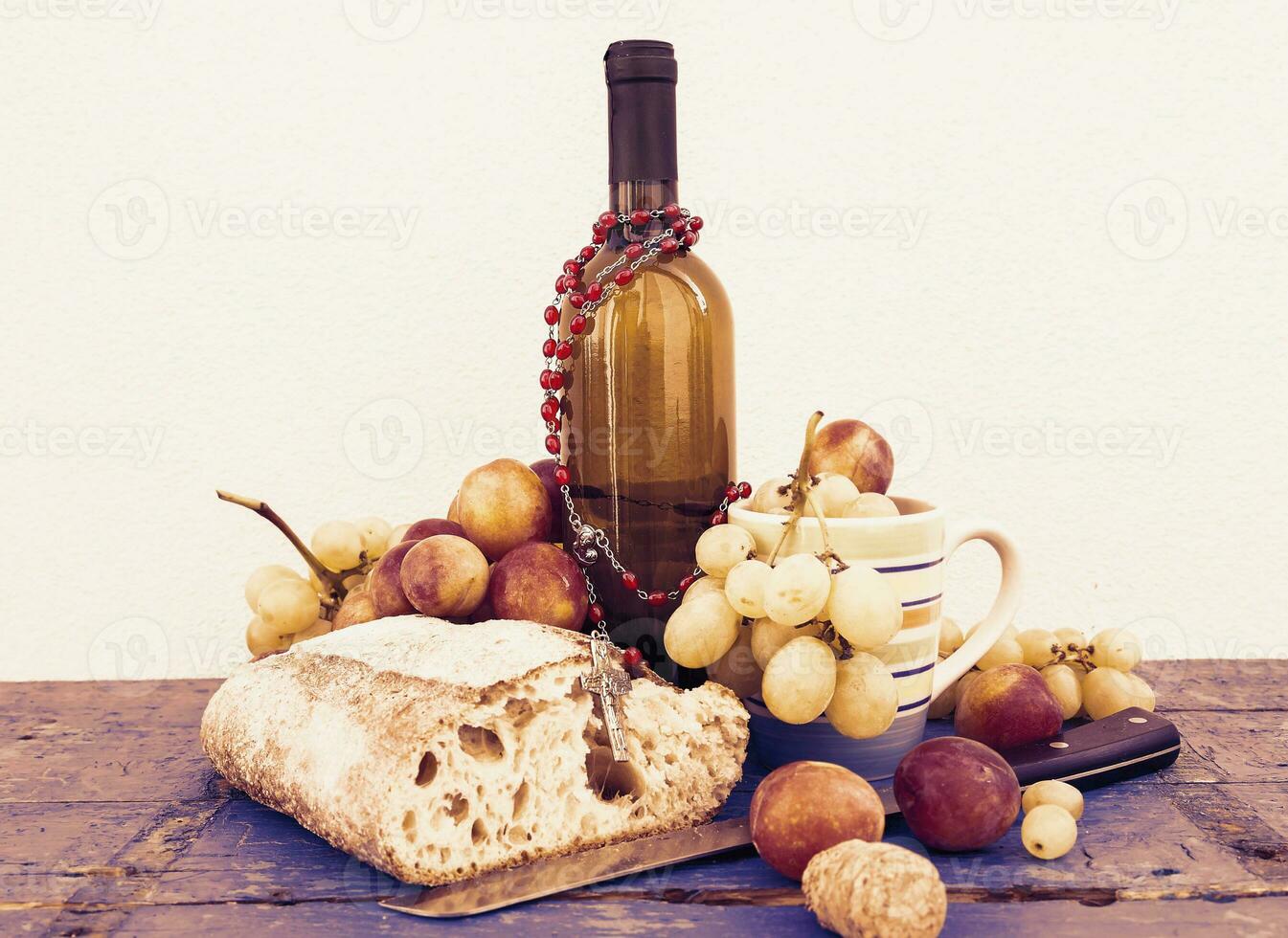 bread grapes and a bottle of wine over wooden boards photo