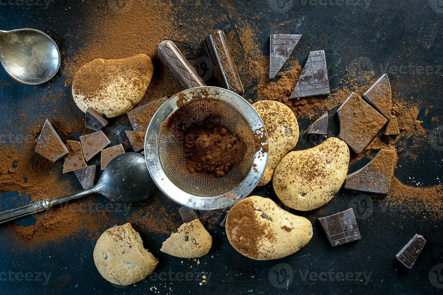 cookies and pieces of chocolate sprinkled with cocoa powder on a black background photo