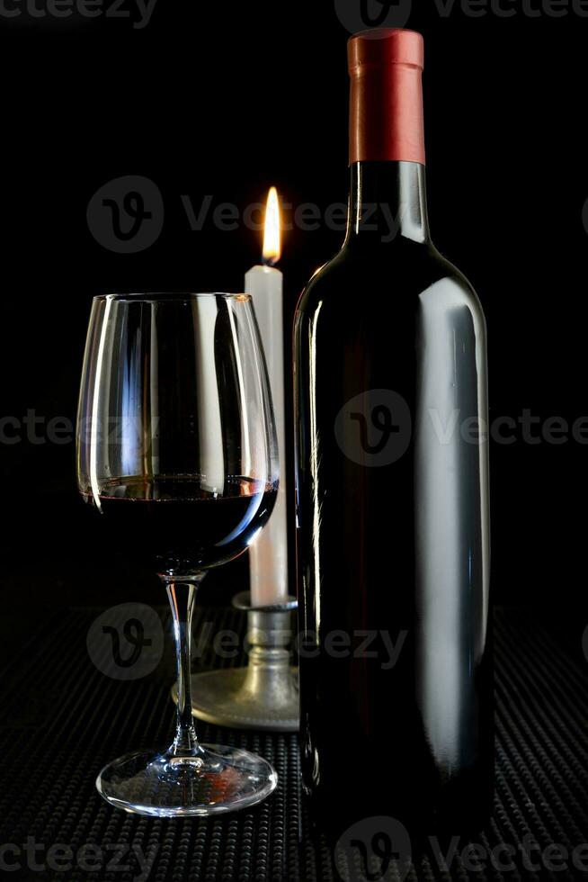 studio composition with red wine bottle and glass and burning candle photo