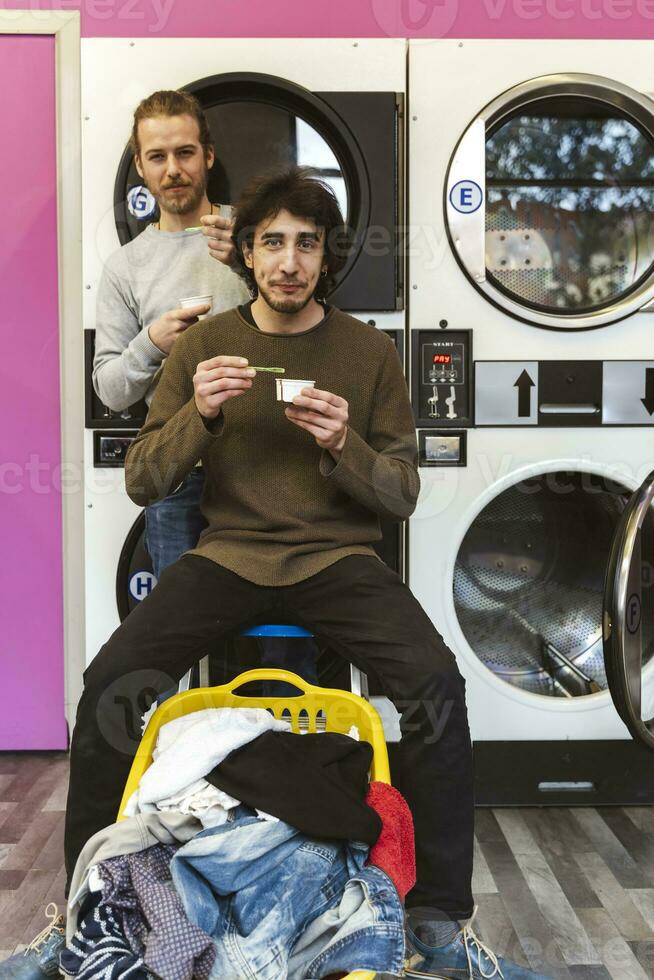 two handsome millennial friends are eating ice cream and washing clothes photo