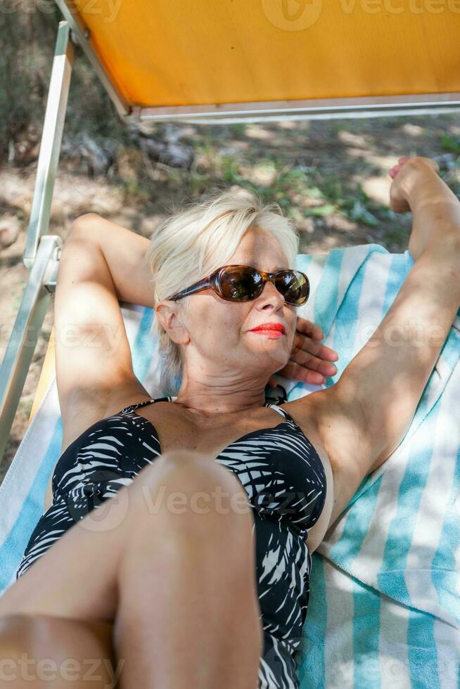 encantador mujer en traje de baño posando en el naturaleza de un parque en verano foto