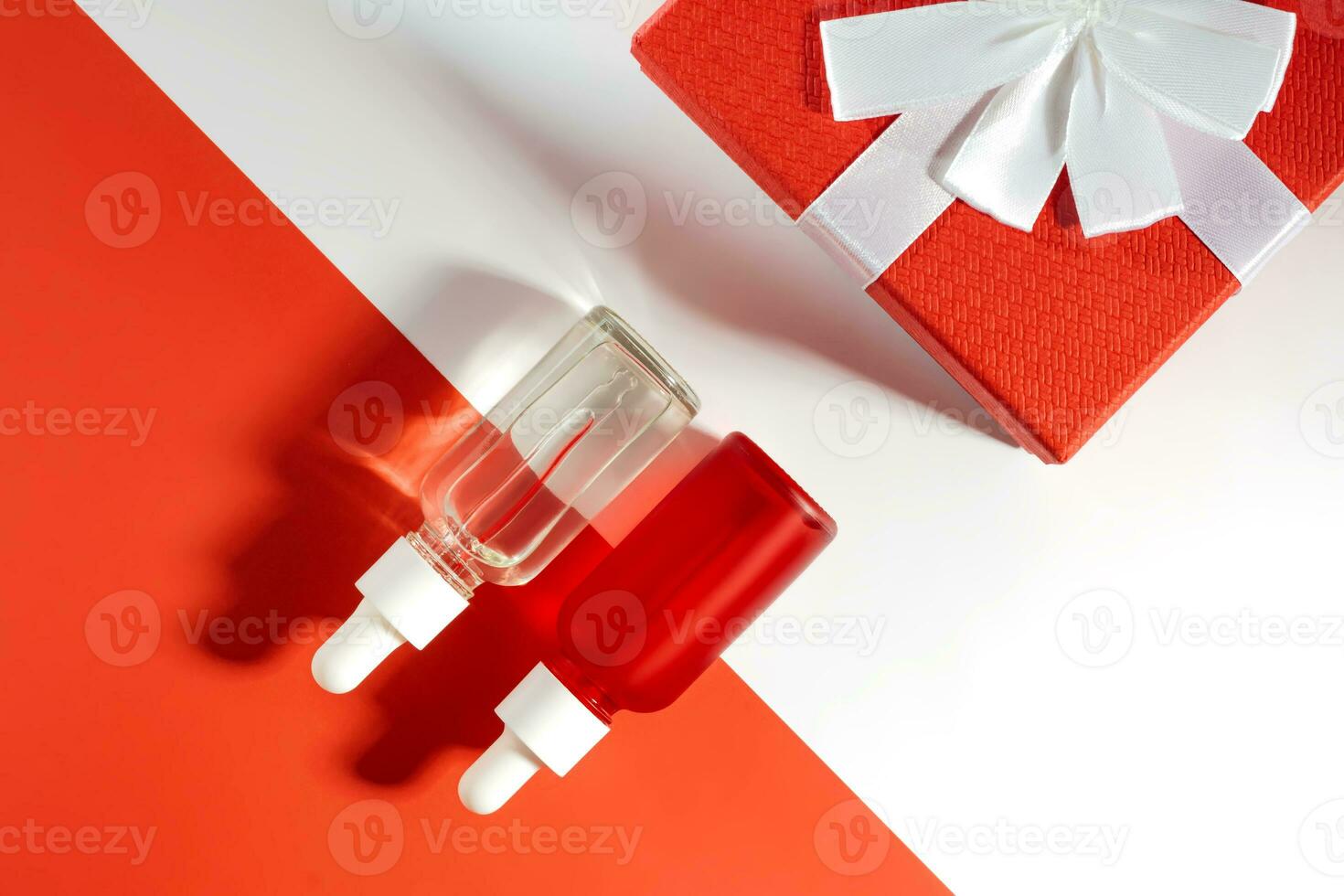 Two Bottles red and white with essential oils next to a red gift box with a bow. Gift for Valentine's Day, Christmas or mothers day. Body and hair care, mockup concept photo