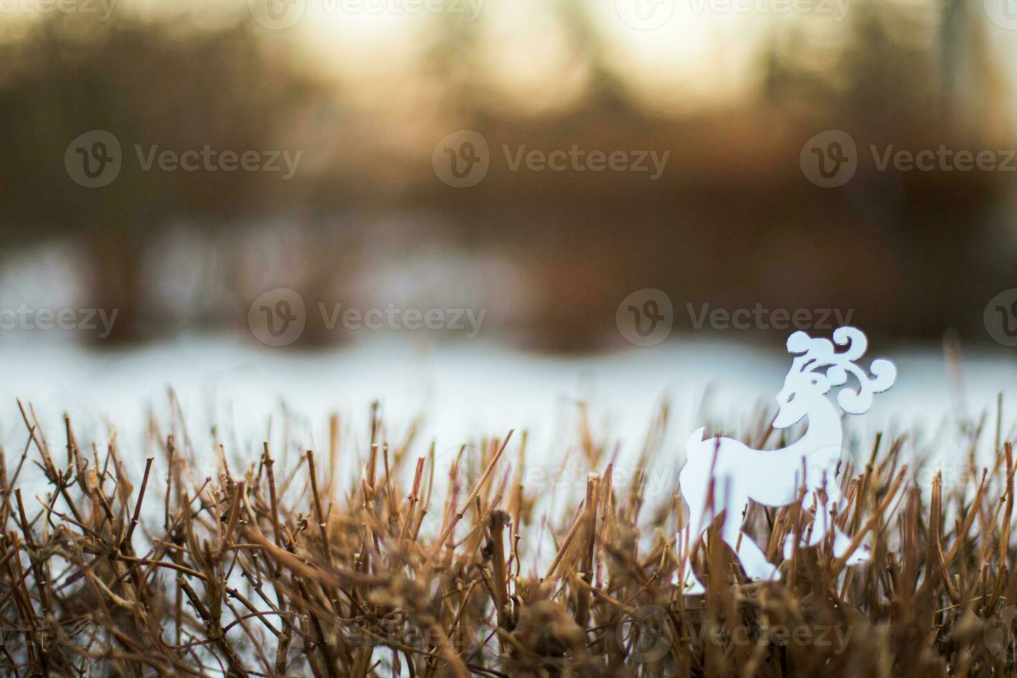 White reindeer figurine standing in the snow in winter forest photo