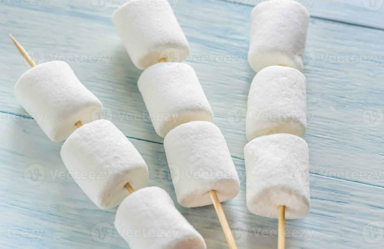 Marshmallow skewers on the wooden background photo