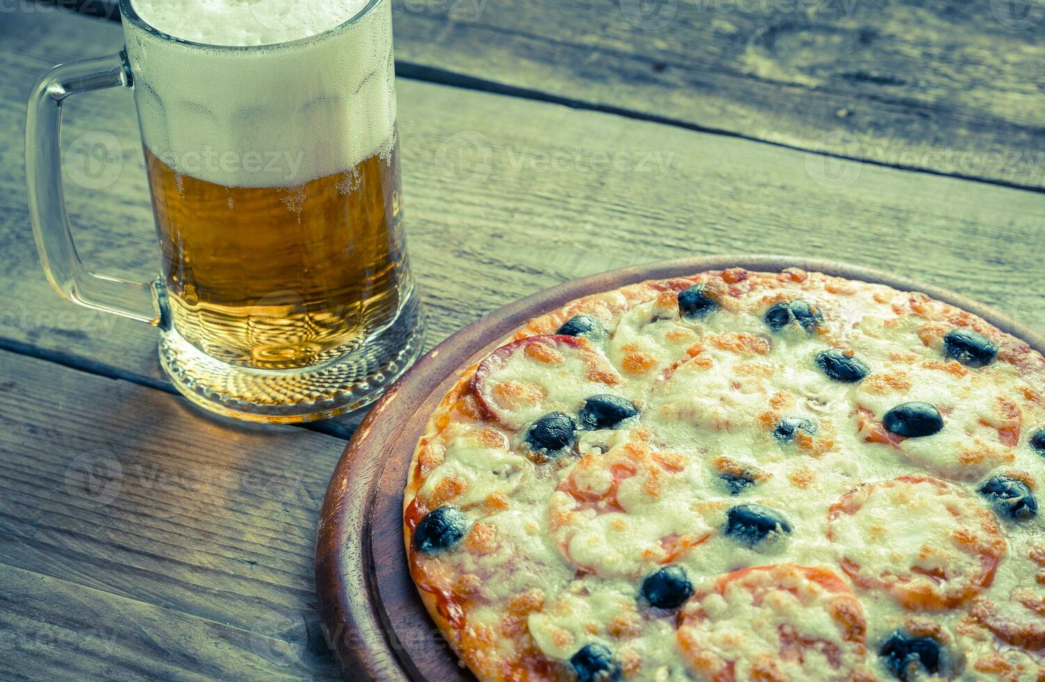 cocido Pizza con un vaso de cerveza foto