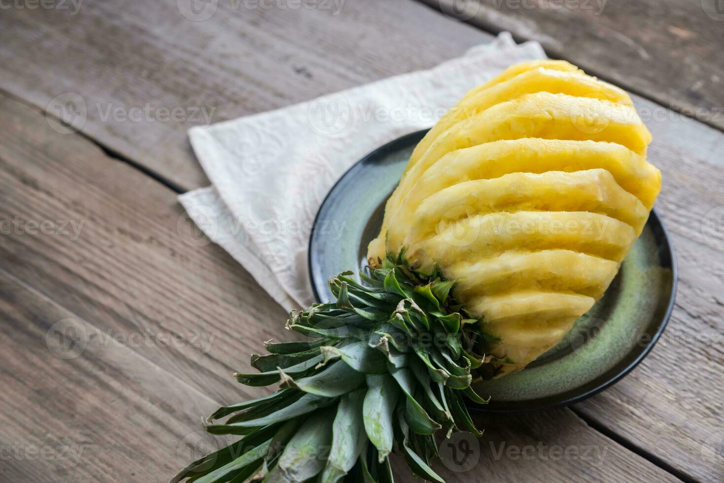 Pineapple on the plate on the wooden background photo