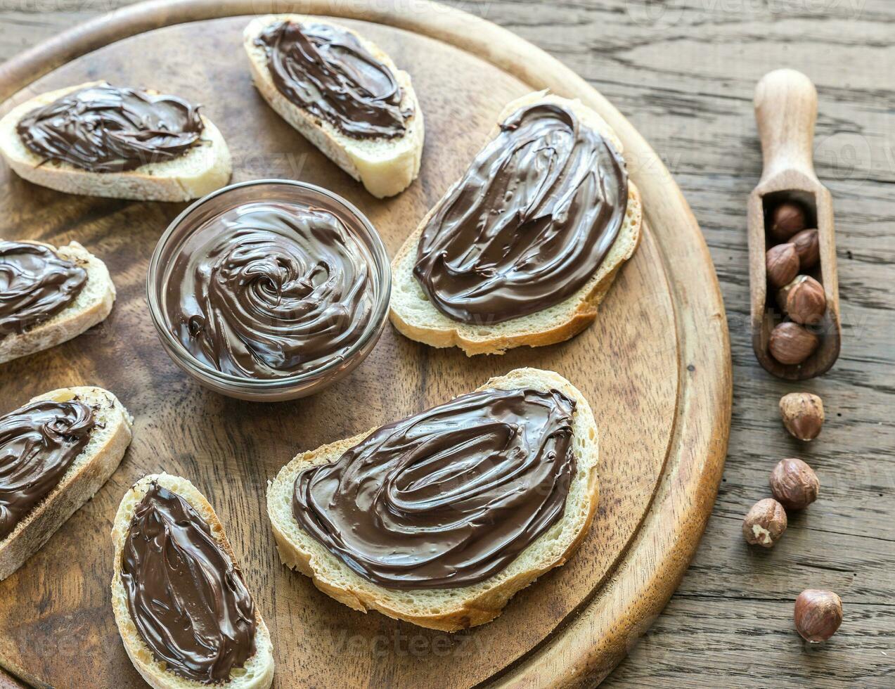 Slices of baguette with chocolate cream on the wooden board photo