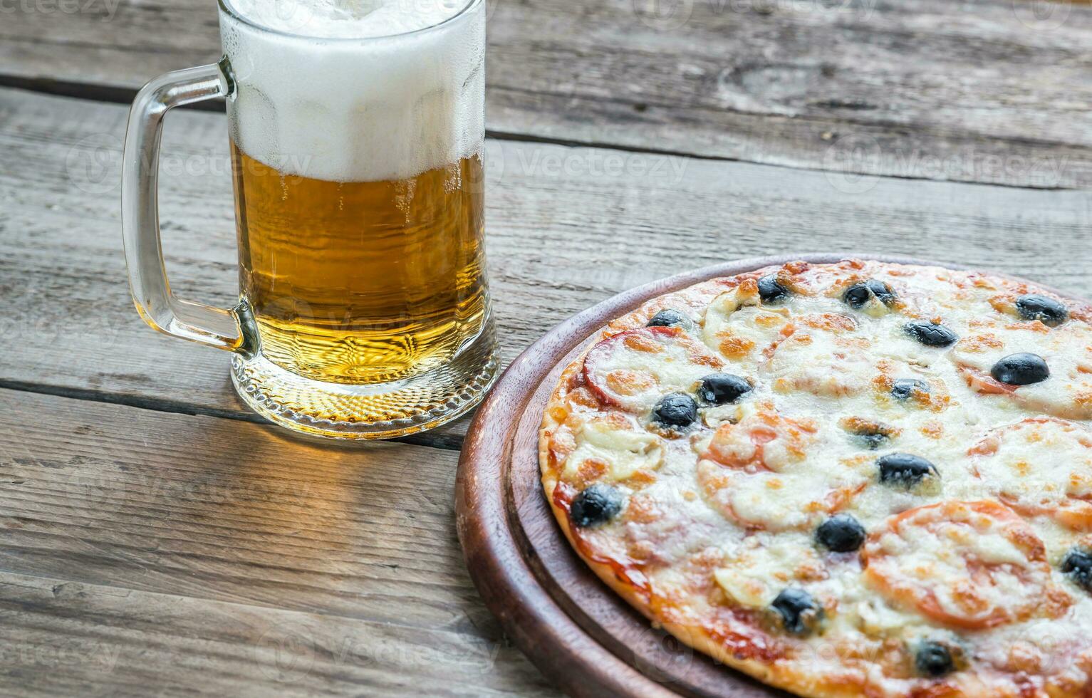 cocido Pizza con un vaso de cerveza foto