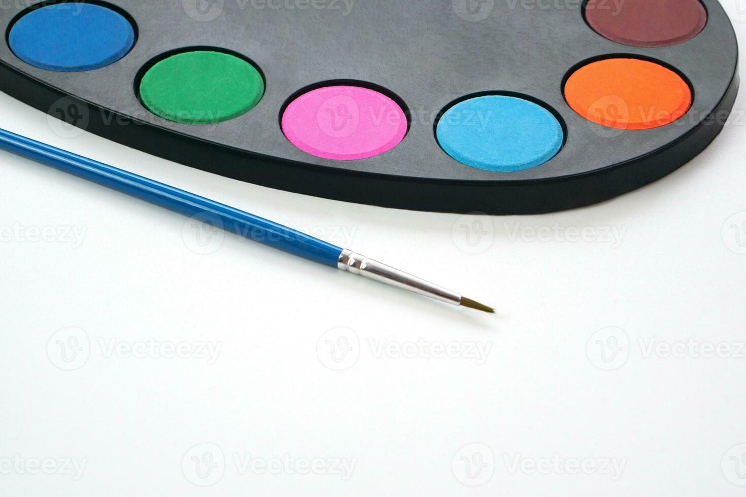 Art palette with paint and brush on blue background. Learning and paintings art concept. photo