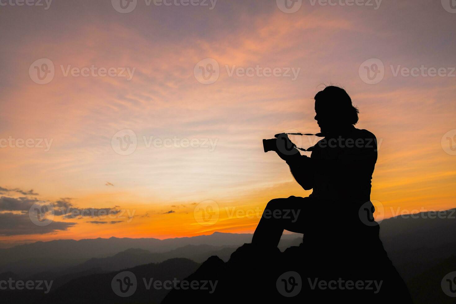 Silhouette of a photographer on top of a mountain at sunset photo