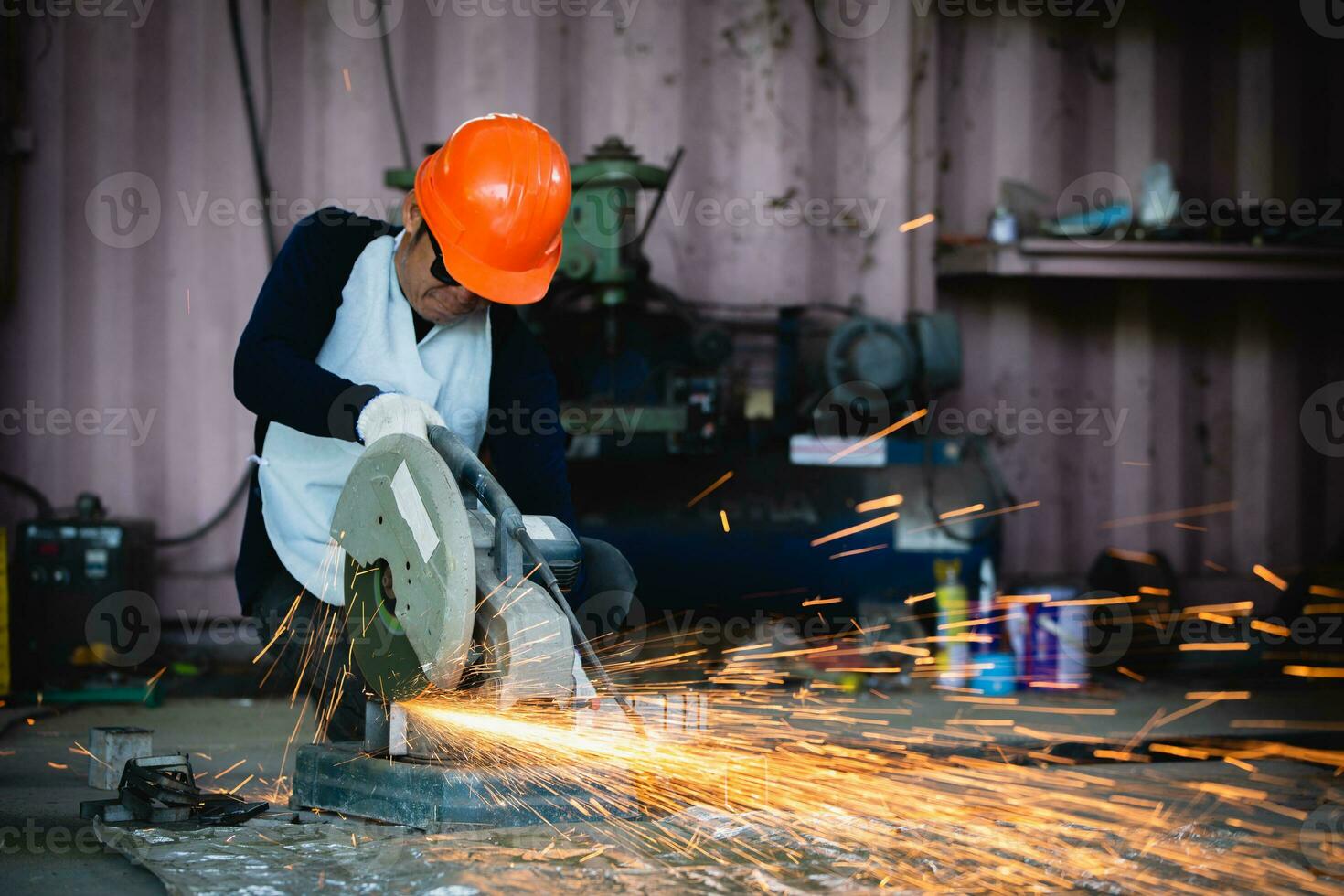 Heavy Industry Engineering Factory Interior with Industrial Worker Using Angle Grinder and Cutting a Metal Tube. Cutting metal and steel with a combination circular saw with a sharp round blade. photo