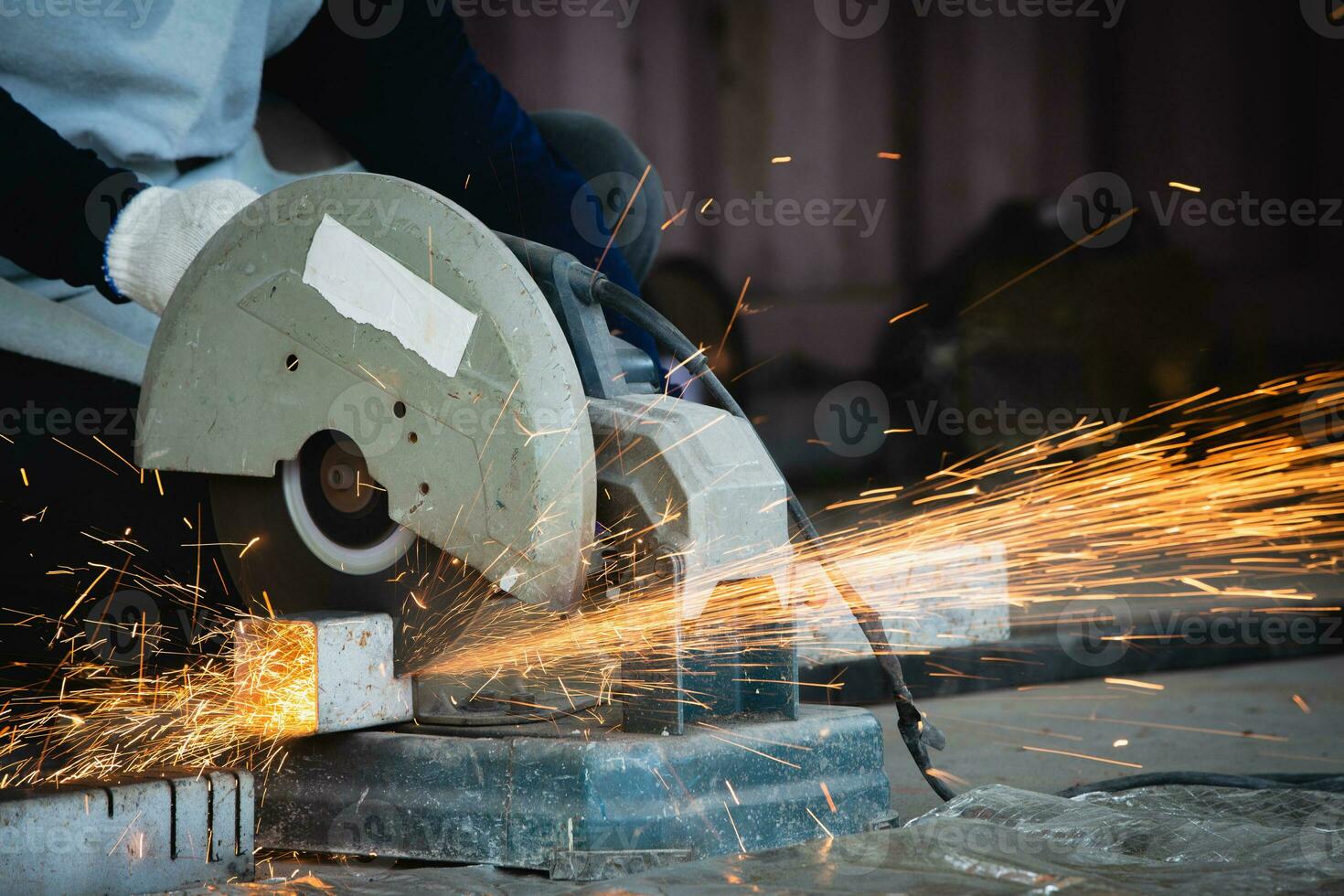 Heavy Industry Engineering Factory Interior with Industrial Worker Using Angle Grinder and Cutting a Metal Tube. Cutting metal and steel with a combination circular saw with a sharp round blade. photo