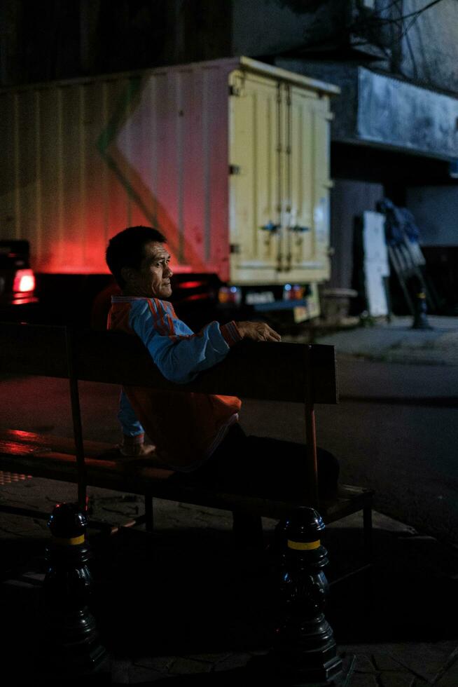 Jakarta, Indonesia - October 4 2023. Night Lights Illuminate Man Seated photo