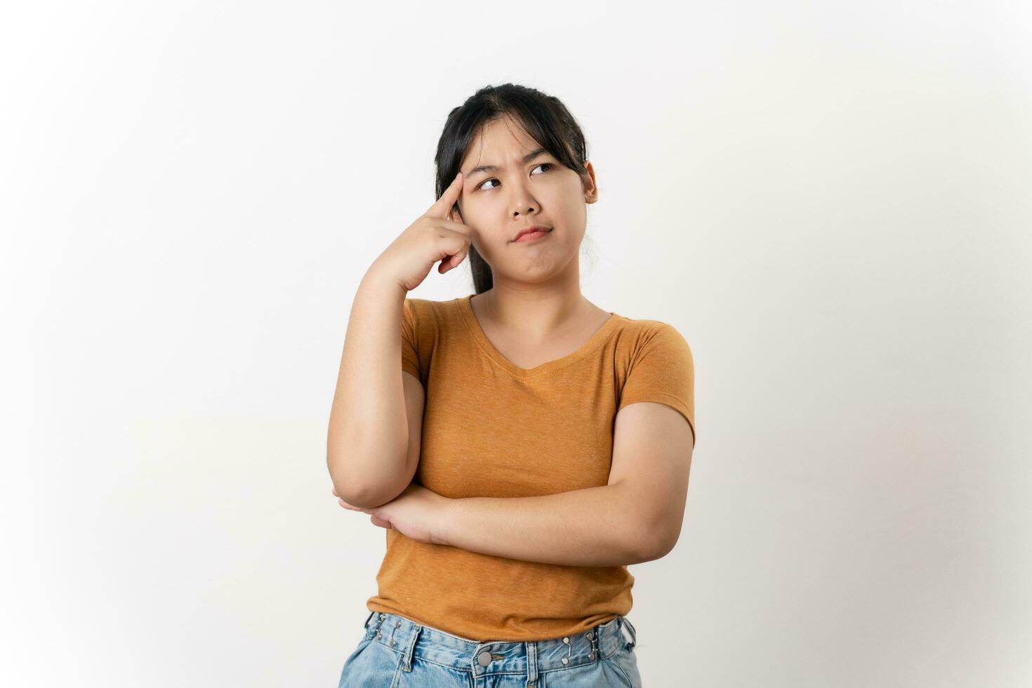 The curious thoughtful young Asian woman looks pensively standing on white background. photo