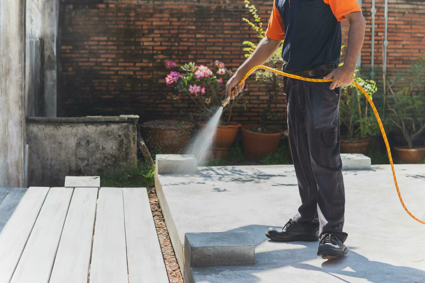 Termite controler spraying cemicals outside the house into the soil and wooden deck. photo