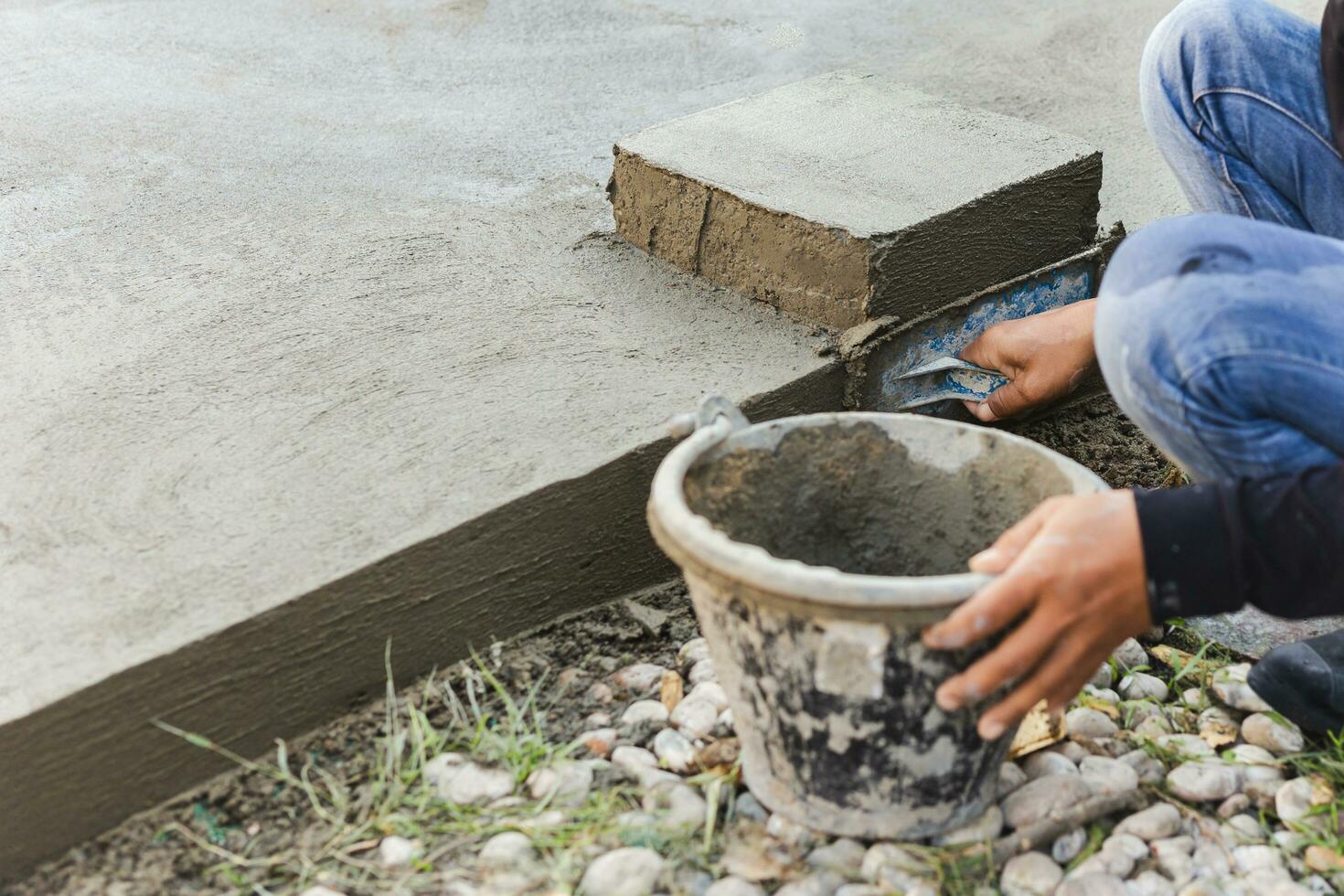Worker leveling concrete cement floor using trowel. photo