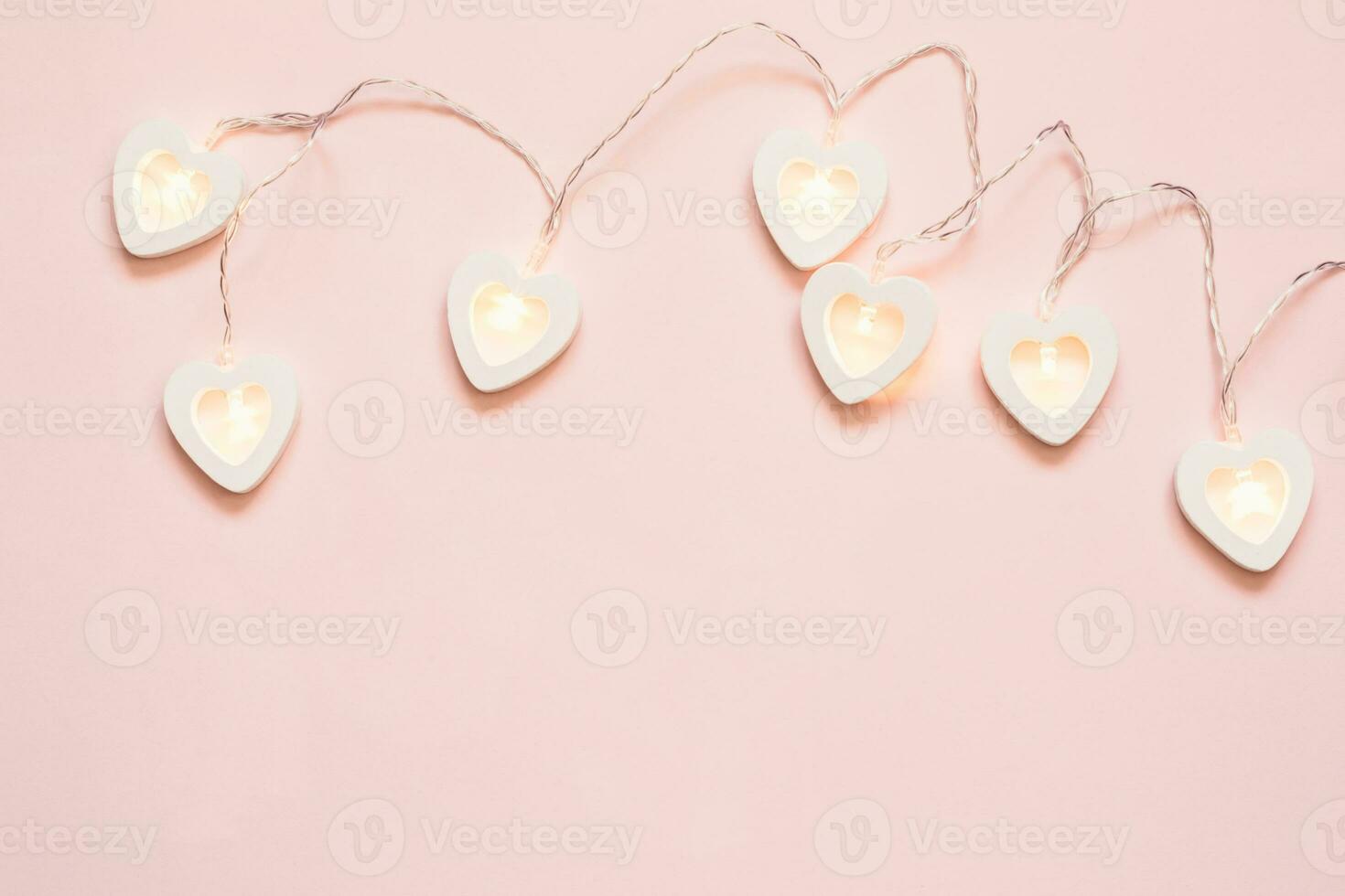 Heart shape garland on a pink pastel background. Valentine's Day or wedding party decoration photo