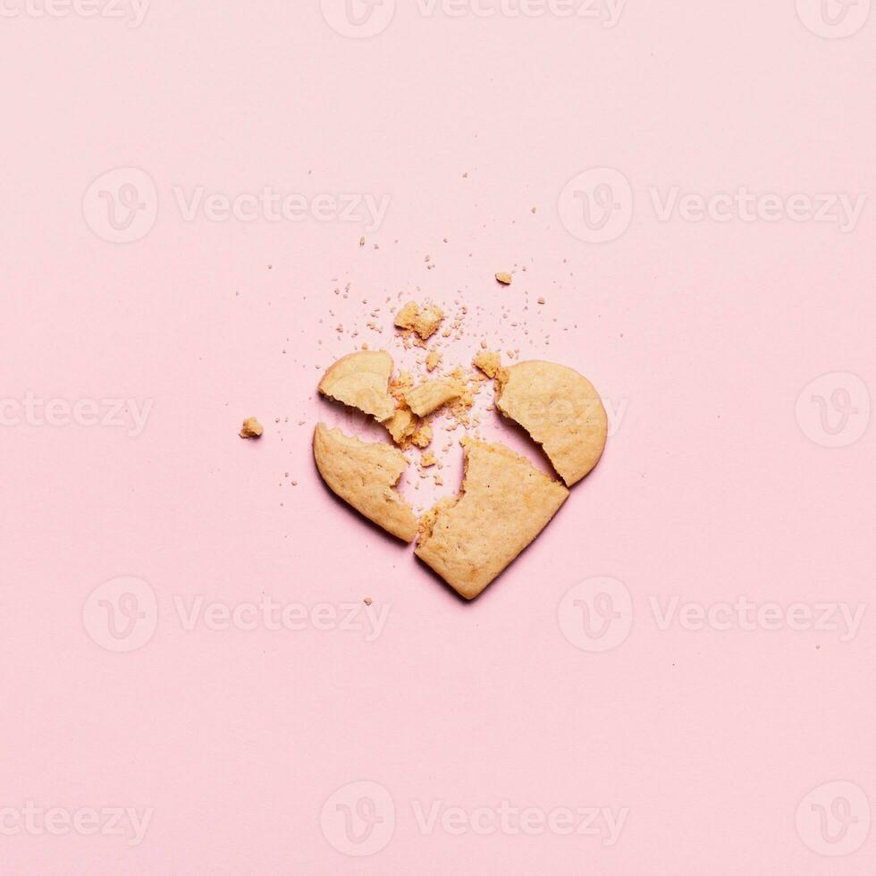 Broken heart cookies on pink background. Unrequited love and cracked relationship concept photo