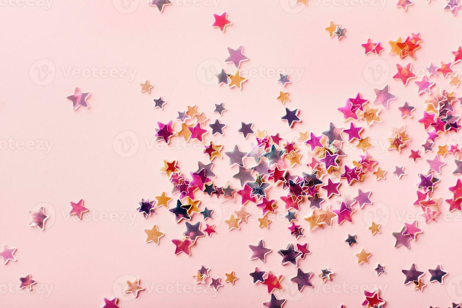 Multicolor holographic Stars Glitter Confetti on pink background. Festive backdrop, selective focus photo