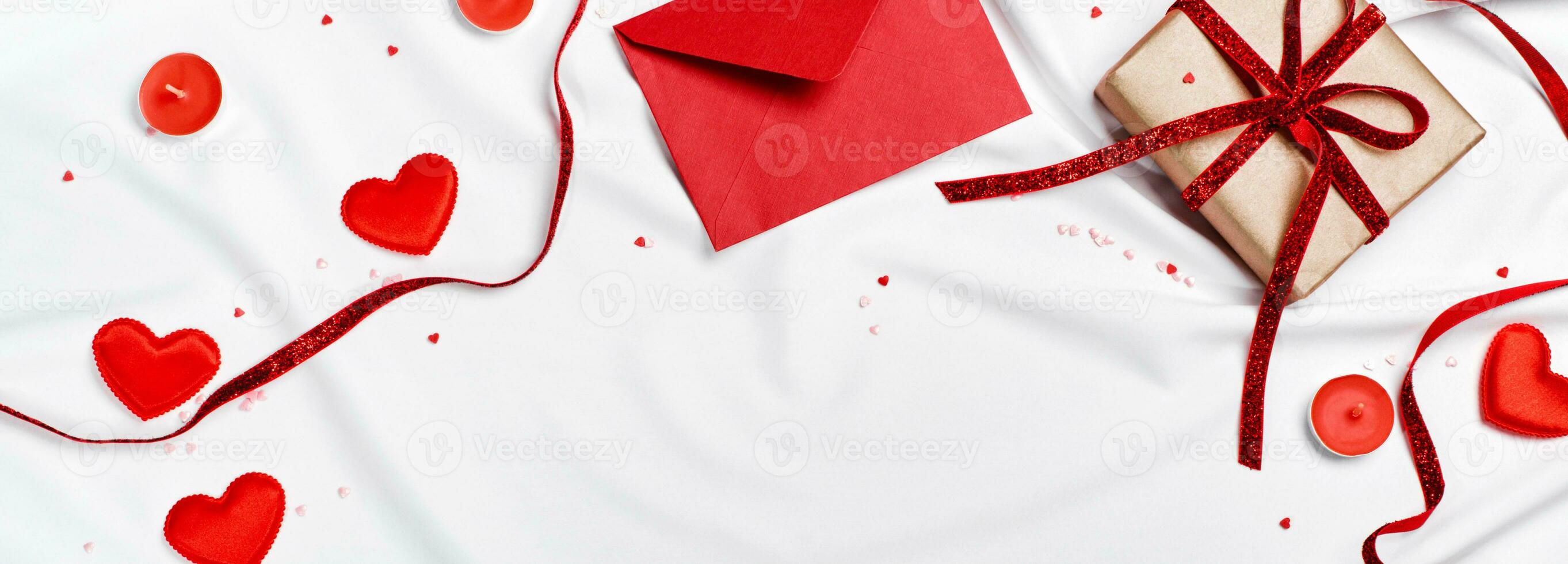 Romantic concept. Valentines day banner. Red envelope, Gift box and hearts on white silk sheet photo