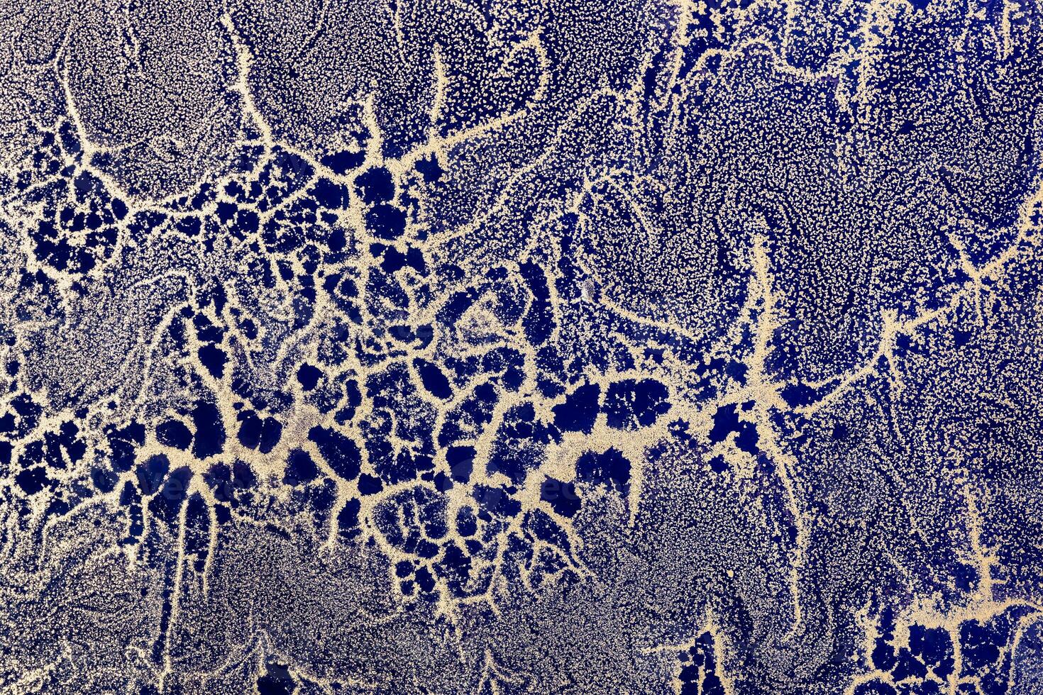 Acrylic Fluid Art. Gold sparkles wavy pattern on dark blue background. Abstract background or texture photo
