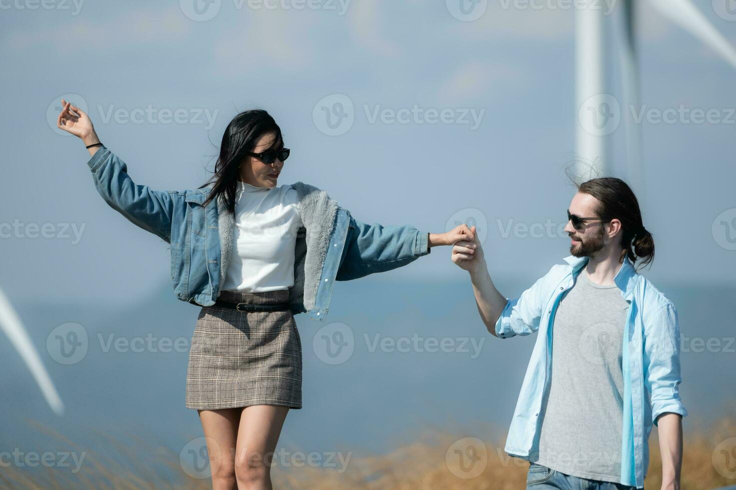 Back view of young couple walking on the road with wind turbines in background photo