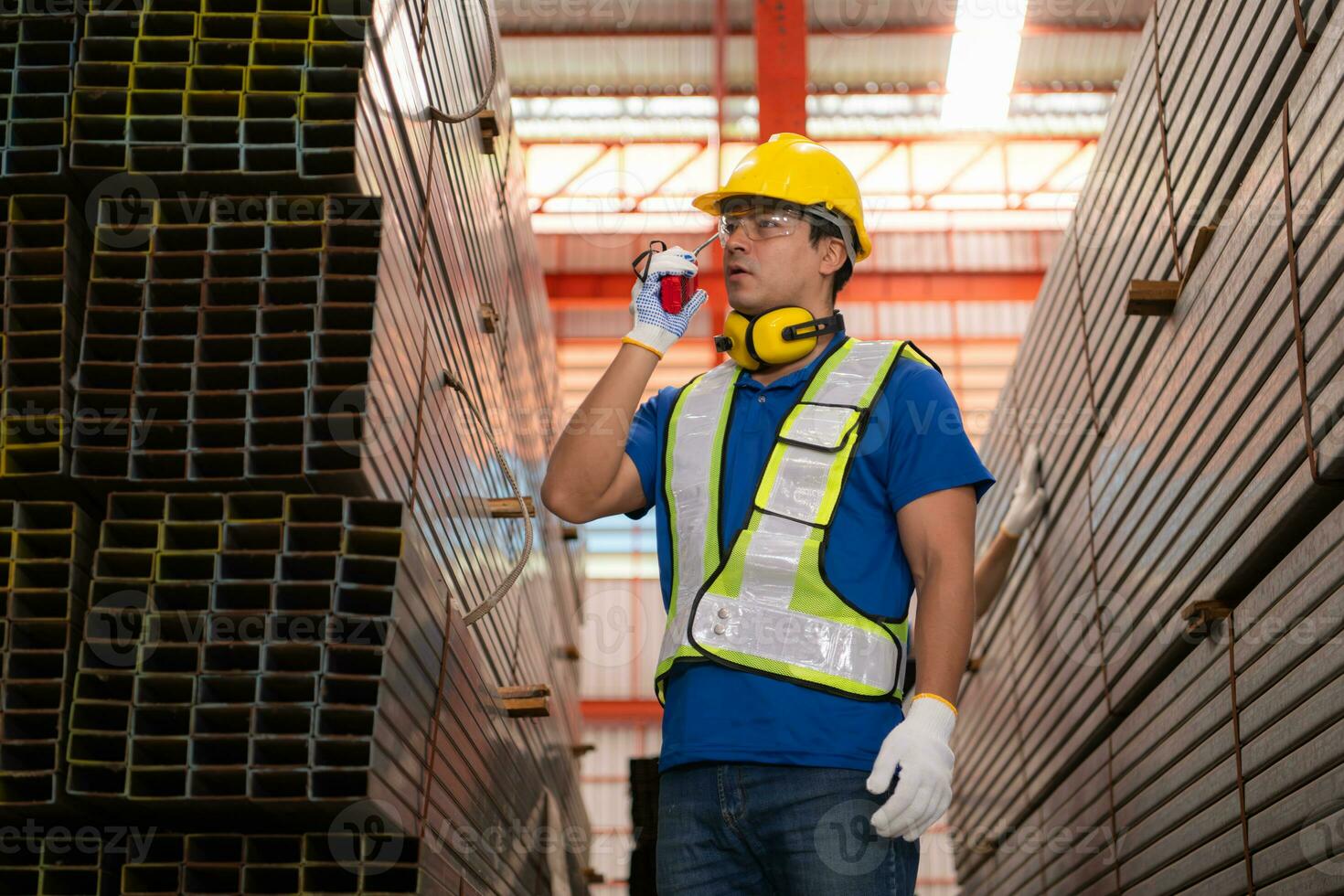 Warehouse workers in hard hats and helmets stand in the warehouse to count and inspect the steel in the warehouse. photo